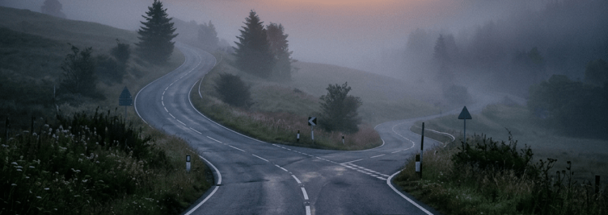 Forked rural road with mist and hills at sunrise