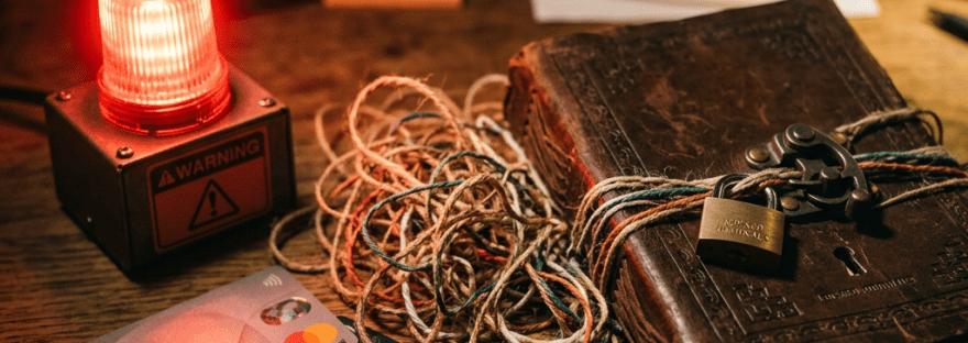 Glowing WARNING beacon beside payment cards, tangled cords, papers, and locked ledger